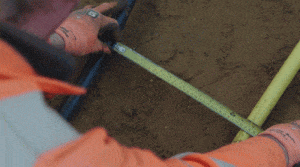 Worker using PPE safety equipment measuring hole