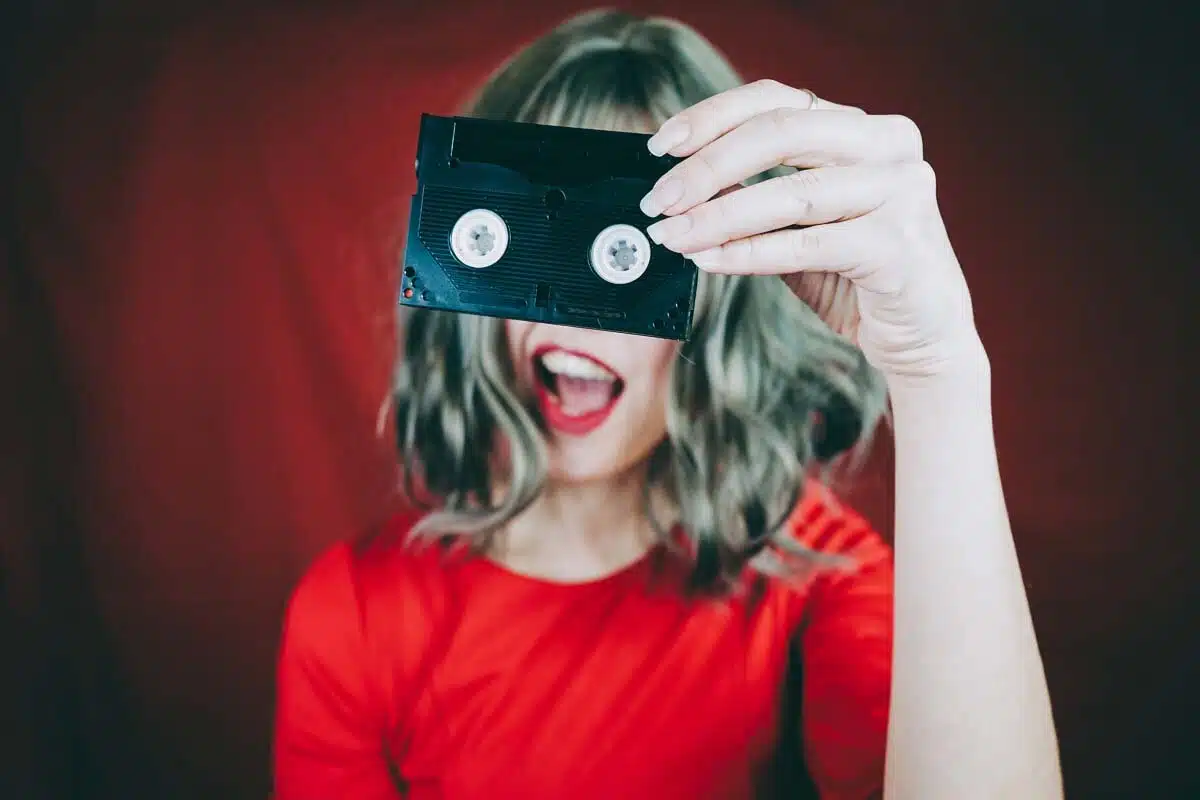 A woman holding up a a retro video tape.